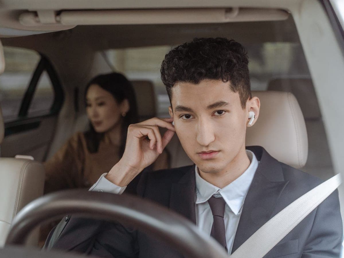 Chauffeur en tenue professionnelle au volant, passagère à l’arrière