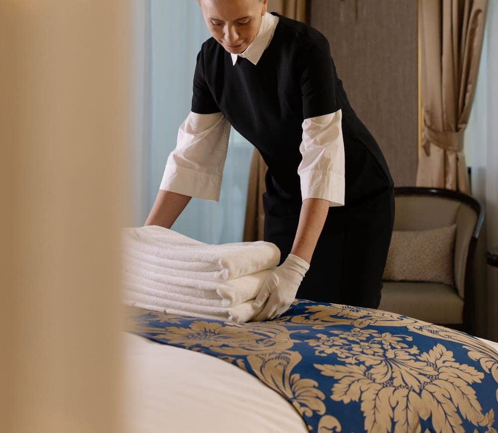 Gouvernante en tenue professionnelle préparant une chambre