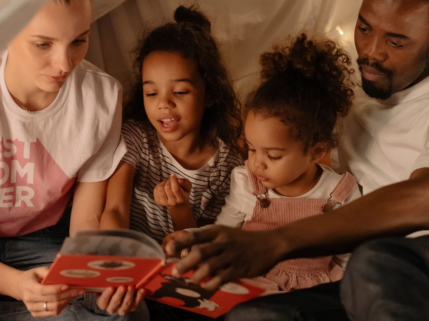 Famille multiculturelle lisant avec ses deux enfants à la maison